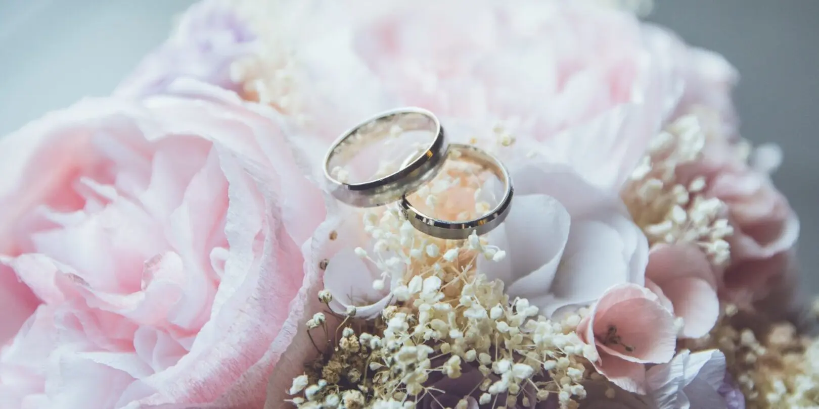 Wedding rings on pink floral bouquet.